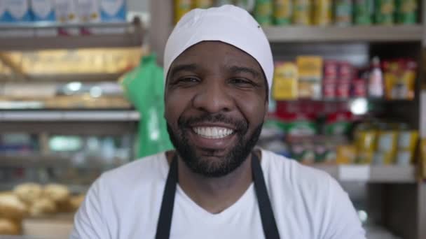 餐厅柜台后面快乐的非裔美国人 穿着制服 产品和消费品 对着相机微笑 背景模糊 — 图库视频影像