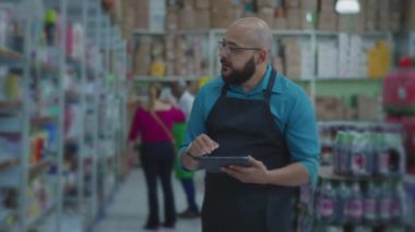 Market koridorundaki tablet cihazıyla envanteri kontrol eden erkek çalışanlar raflara bakan ve süpermarketteki ürünleri incelemek için modern teknolojiyi kullanan personel.