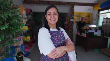 Little Local Business 'ın kadın işçisinin portresi. Kolları çaprazlanmış dükkanın önünde kameraya gülümsüyor. Otantik gerçek girişimciler