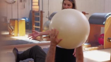 Kadın fizyoterapist yardımı altında, Yaşlılıkta Sağlık ve Sağlığın Vurgulanması Altında Pilates Balosu ile Üst Düzey Egzersiz Yapıyor