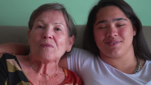 ハッピーな民族的に多様な世代の孫娘と一緒にカメラのためにポーズする祖母 頬に祖父母にキスするおじいちゃん — ストック動画