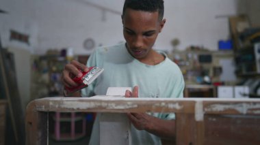 Genç bir siyah Brezilyalı marangoz atölyede ahşap cilalıyor, Konsantre Çalışan Mobilya Tamiri ile meşgul