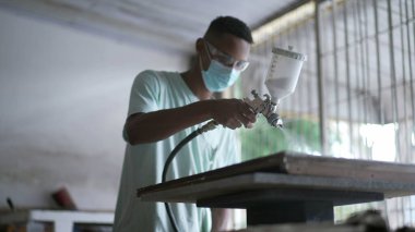 Marangozhanedeki Ahşap Yüzeye Boya Spreyi uygulayan Genç Siyah İşçi
