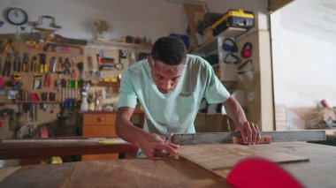 Bir Odaklanmış Siyah Brezilyalı Marangoz Atölyede Ağaç Kesiyor. Marangozluk işinde çalışan genç bir çırak.