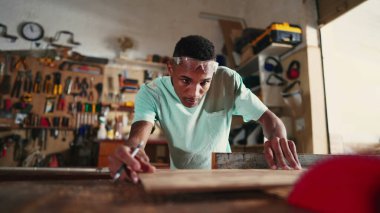 Konsantre Genç Brezilyalı Marangoz Atölye 'de Ahşap Kesen Testere Makinesi kullanarak Meslek Öğreniyor