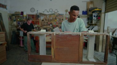 Marangozluk atölyesinin genç çalışanı ahşap mobilyaları parlatıyor, eski nesneleri onarıyor ve tadilat yapıyor. Küçük işletmelerde iş.