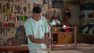 Marangozhane atölyesinde çalışan genç bir siyah çırak. İşçilik mesleği mobilya yapmak.