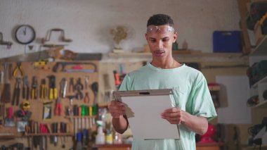 Marangoz gemisinde çalışan genç bir çırak endüstriyel ekipmanlarla odun kesiyor ve ölçüyor. El işi, iş mesleği konsepti olan kişiler