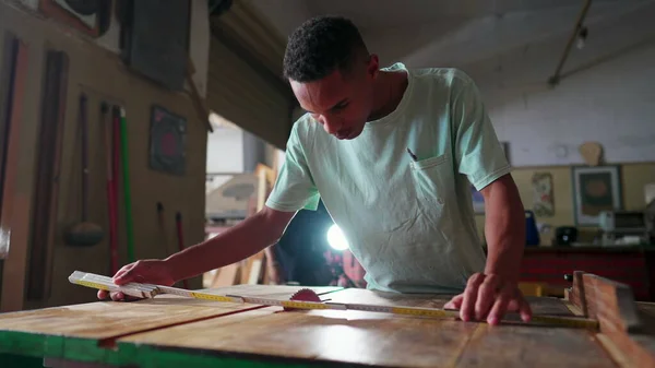 木工学徒测量一块木头 准备用锯机锯片 一个巴西年轻人在木工车间用测量磁带 — 图库照片