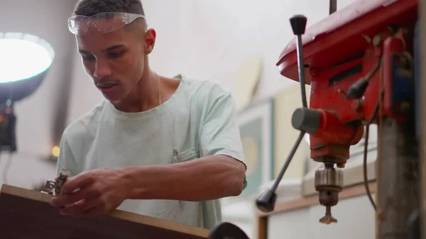 stock image One Brazilian black young carpenter working at woodworking carpentry workshop next to industrial machine, job occupation of apprentice engaged at work