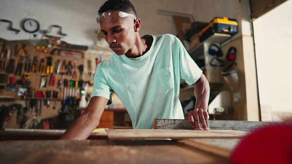 Concentrated Young Brazilian Carpenter Learning Profession in Workshop, using saw machine slicing wood