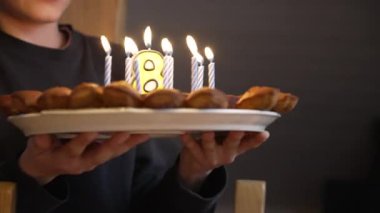 8 yaşındaki çocuk için doğum günü pastası getiren yakın çekim elleri.