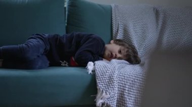Küçük çocuk kanepede uzanmış kameradan çizgi film izliyordu. Çocuk eğlence içeriğiyle hipnotize edildi. Evde rahatladı.