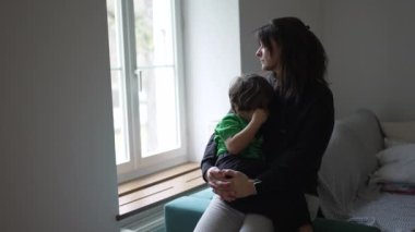 Anne yaralı çocuğu evde pencerenin önünde teselli ediyor. İçten, düşünceli, düşünceli bir annenin, küçük çocuğu teselli ettiği bir an.