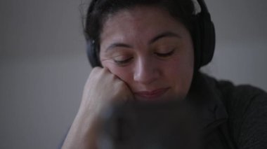 Cep telefonu cihazına bakarken ağlayan bir kadın, kulaklık takan, cep telefonu takan, içeriği dinleyen ya da video konferansı yapan duygusal bir insan.