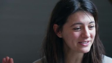 Kameranın önünde insanlarla konuşan mutlu bir kadının yakın plan yüzü. Gülümseyen bir kadın diğerleriyle konuşurken güler ve gülümser.
