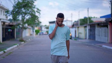 Siyah Brezilyalı bir adam, düşünceli bir ifadeyle sokakta yürüyor, Zor bir kararı derin derin düşünüyor.