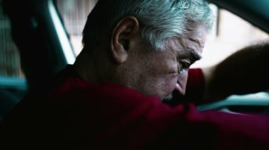Arabada duygusal çöküntüden muzdarip yaşlı bir adam, yaşlı bir insan, direksiyona yaslanmış sessiz umutsuzluk ve sosyal kopukluk içinde. Savunmasız, endişeli, yaşlı kişi.