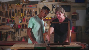 Marangozluk atölyesinde usta marangoz ve işçi. İnsanlar Çırakla İş Bulma Kurumu 'nda çalışıyor.