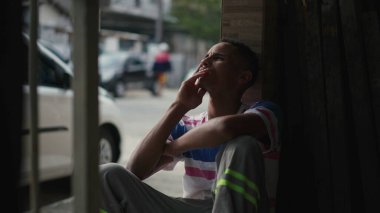 Dalgın genç Afrikalı Amerikalı erkek kaldırımdan duvara yaslanarak derin zihinsel yansımasını seyrediyor. Düşünceli siyah bir insan, hayatı düşünüyor.
