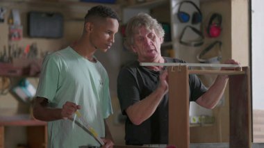 Usta marangoz, çıraklara marangozluk atölyesinde mobilya inşa ve onarım sürecini öğretiyor.