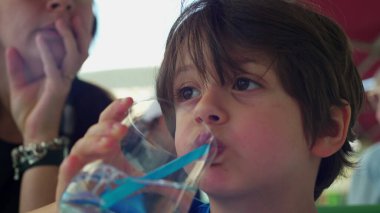 Restoranda kendine su ve saman döken küçük çocuk, Sıcak Yaz Günü 'nde yakın çekim yüzü.
