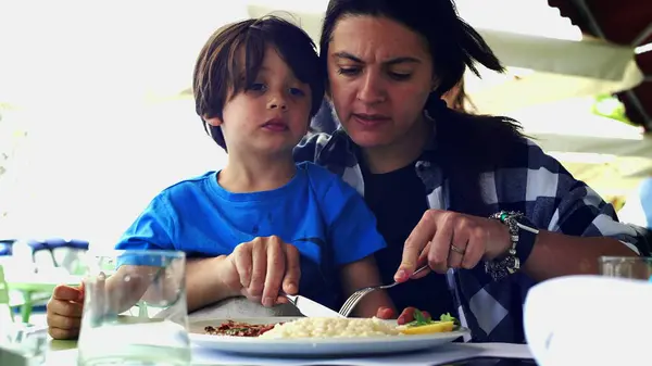 Mother Feeding Child in Restaurant, Candid Family Meal During Vacation, Child on Mom's Lap