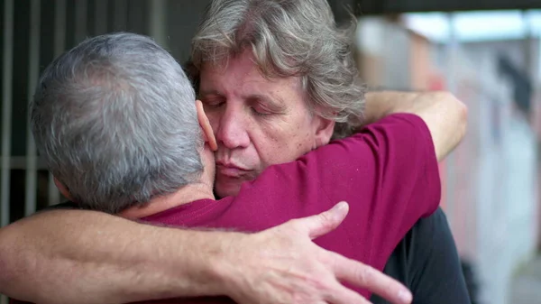 Heart-warming embrace between two senior friends in authentic loving hug. Two elderly people saying farewell embracing, candid and real life family affection
