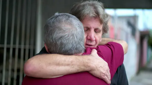 Heart-warming embrace between two senior friends in authentic loving hug. Two elderly people saying farewell embracing, candid and real life family affection