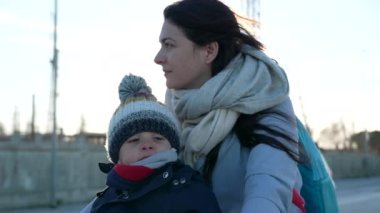 Anne ve 2 yaşındaki çocuk soğuk kış gününde bisikletle dışarıda. Eşarp ve ceket giyen çocuk ve ebeveyn bisiklet sürüyor.