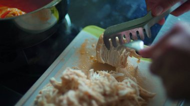 Tavuk parçalarını çatalla parçalamak, yakın plan yemek hazırlamak.