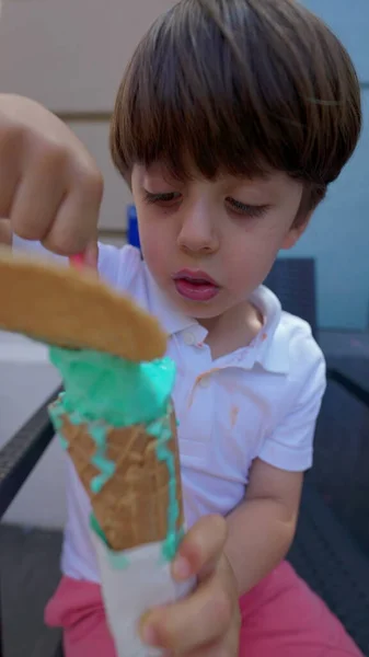 stock image Small boy indulging himself with colorful ice-cream cone during sunny summer day. Child eating sweet dessert treat, vertical video