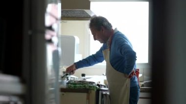 Önlüklü emekli aşçı ev yemeklerine odaklandı. Son sınıf öğrencisi mutfak sobasıyla yemek hazırlıyor.