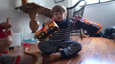 Küçük çocuk kamyon oyuncaklarıyla oynuyor, birlikte araba çarpıyor. Evde oyun oynayan çocuk, beyaz erkek çocuk nesnelerle oynuyor.