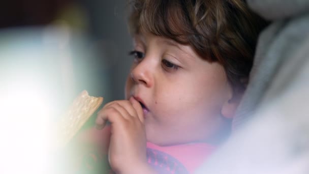 沉思的孩子躺在沙发上吃曲奇 细细的小男孩的脸在沉思时吃甜食 — 图库视频影像