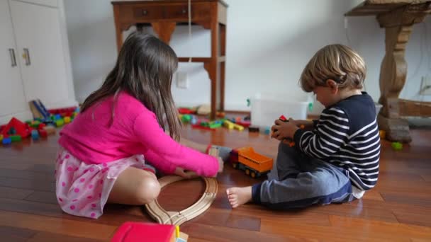 子供は床で家で遊んで 小さな男の子と女の子は遊び 兄弟姉妹はおもちゃを共有しました — ストック動画