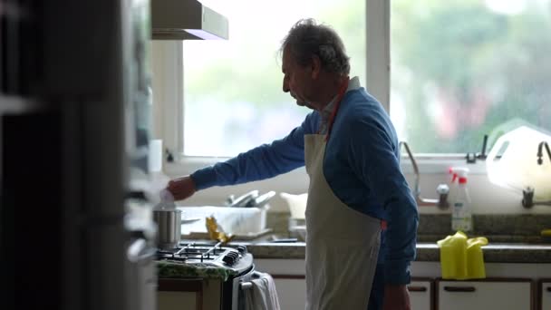 Bărbat Senior Care Gătește Mâncare Picioare Lângă Aragazul Bucătărie Amestecând — Videoclip de stoc