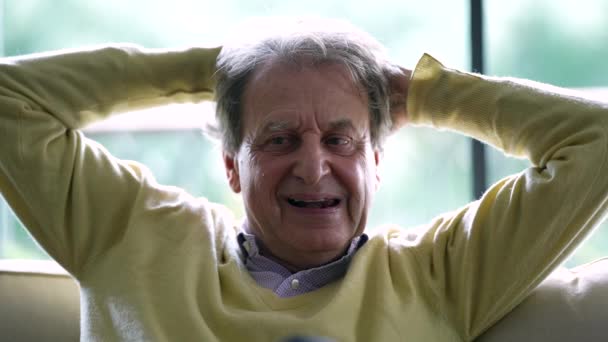 Pensive Senior Mand Sidder Sofaen Med Hænderne Fastspændt Bagsiden Hovedet – Stock-video