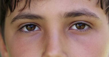 Boy closing and opening eyes close-up. Meditative Macro closeup of child eye looking to camera