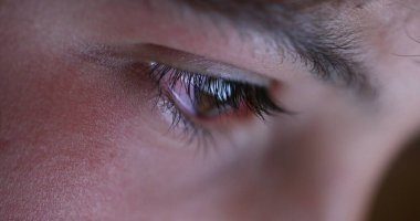 Boy closeup eye watching content online. Child macro eyes close-up staring and looking at tablet screen at night