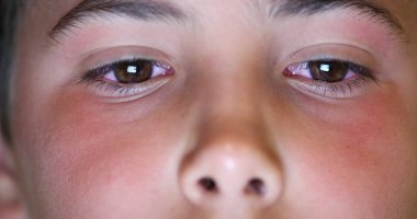 Boy eyes macro close-up watching content online. Child staring at blue light device screen