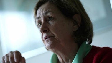 Üst düzey kadın kamera önünde konuşulanları dinliyor, samimi yaşlı bayan arkadaşlarıyla konuşuyor, samimi ve otantik etkileşimler içinde.