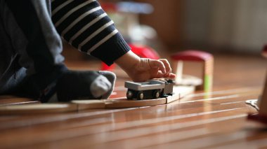 Antik Tren Oyuncağı 'yla oynayan çocuk elleri, Kapalı Kapılar ardında demiryolu setiyle meşgul olan genç, evde tek başına oynayan samimi çocuk.