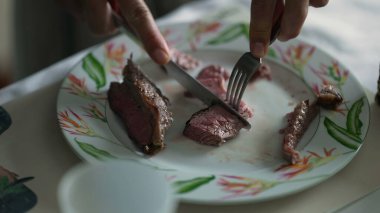 Kapalı el tabakta et parçaları kesiyor. Bıçak ve çatal dilimleyen insan öğle yemeği yiyor.
