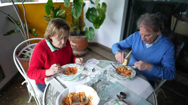 Yaşlı bir çift, apartmanın balkonunda öğle yemeğinin tadını çıkarıyor, emekli karı koca, terasta yemek saatleri paylaşıyor, ev hayatı tarzı yaşlılık sahneleri.