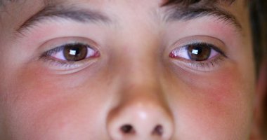 Child boy eyes looking at tablet device screen. Kid staring at blue light macro eye close-up