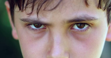 Concerned child relaxing frown being more at peace with good news, macro closeup of kid face