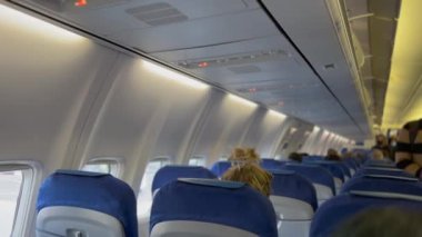  Inside plane cabin. Passengers getting ready to seat. Boarding on airplane.