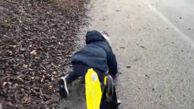 Child falling down in the ground while riding toy scooter. One small boy accident getting hurt.