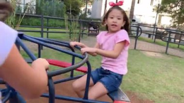 Small girls playing in playground carousel roundabout in motion